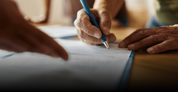 Hands signing a document with pen.