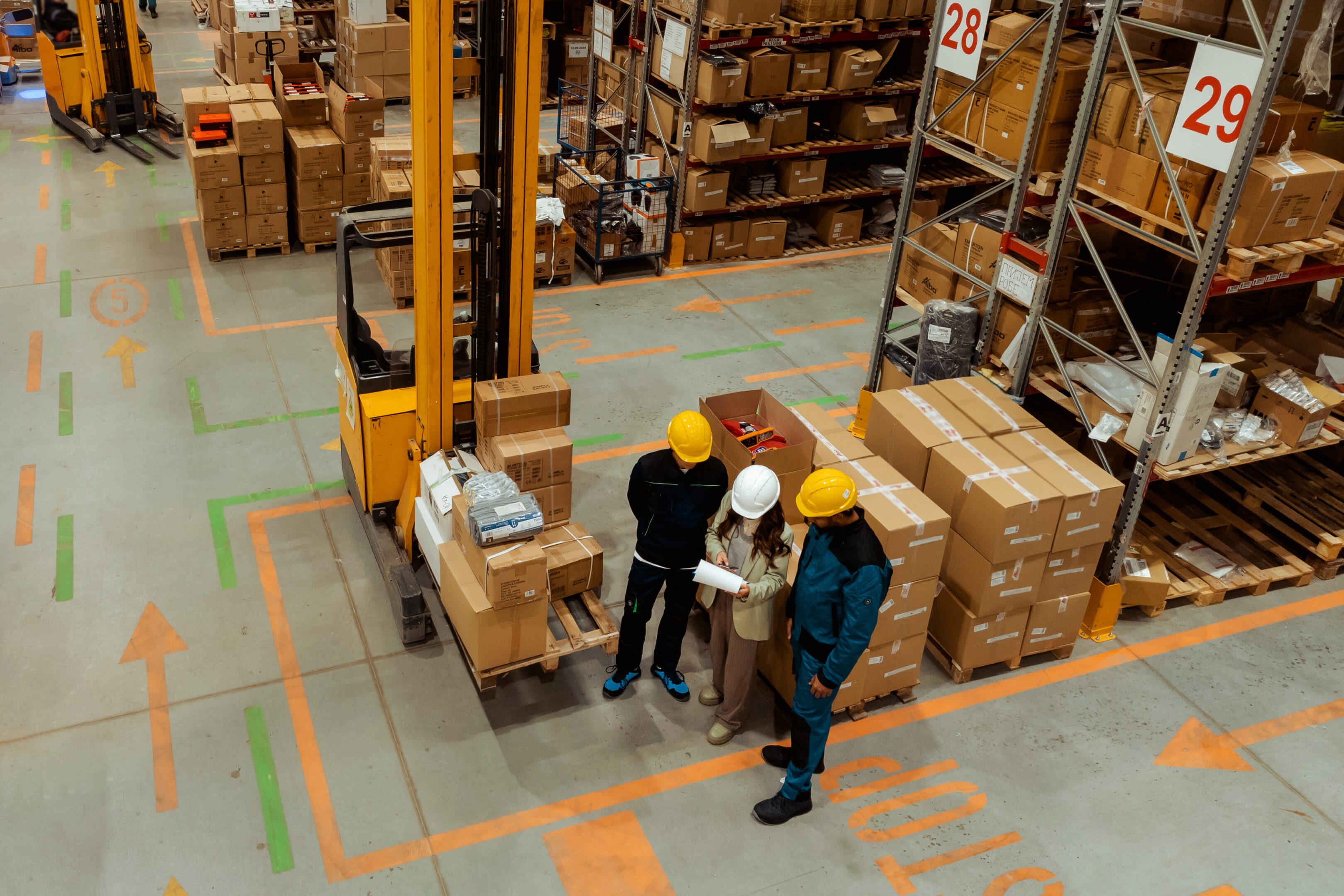 Warehouse workers discussing logistics near forklift.